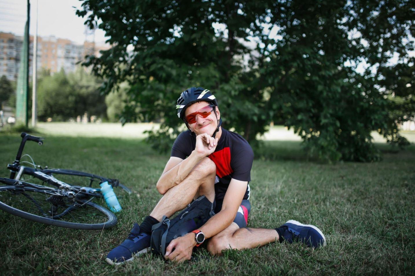 Young man relaxing on the grass outdoors beside his bike