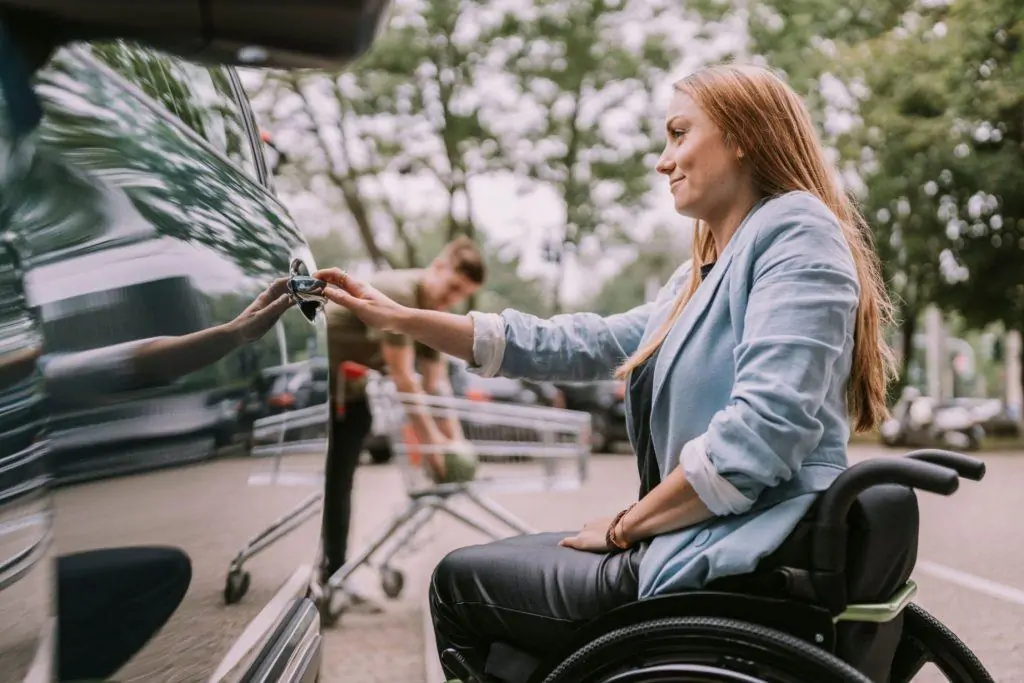 NDIS participant in a wheelchair beside a car