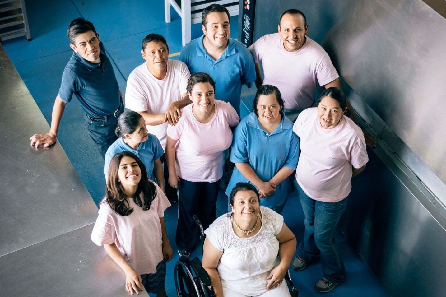 Group of smiling people in blue and white shirts looking up at the camera