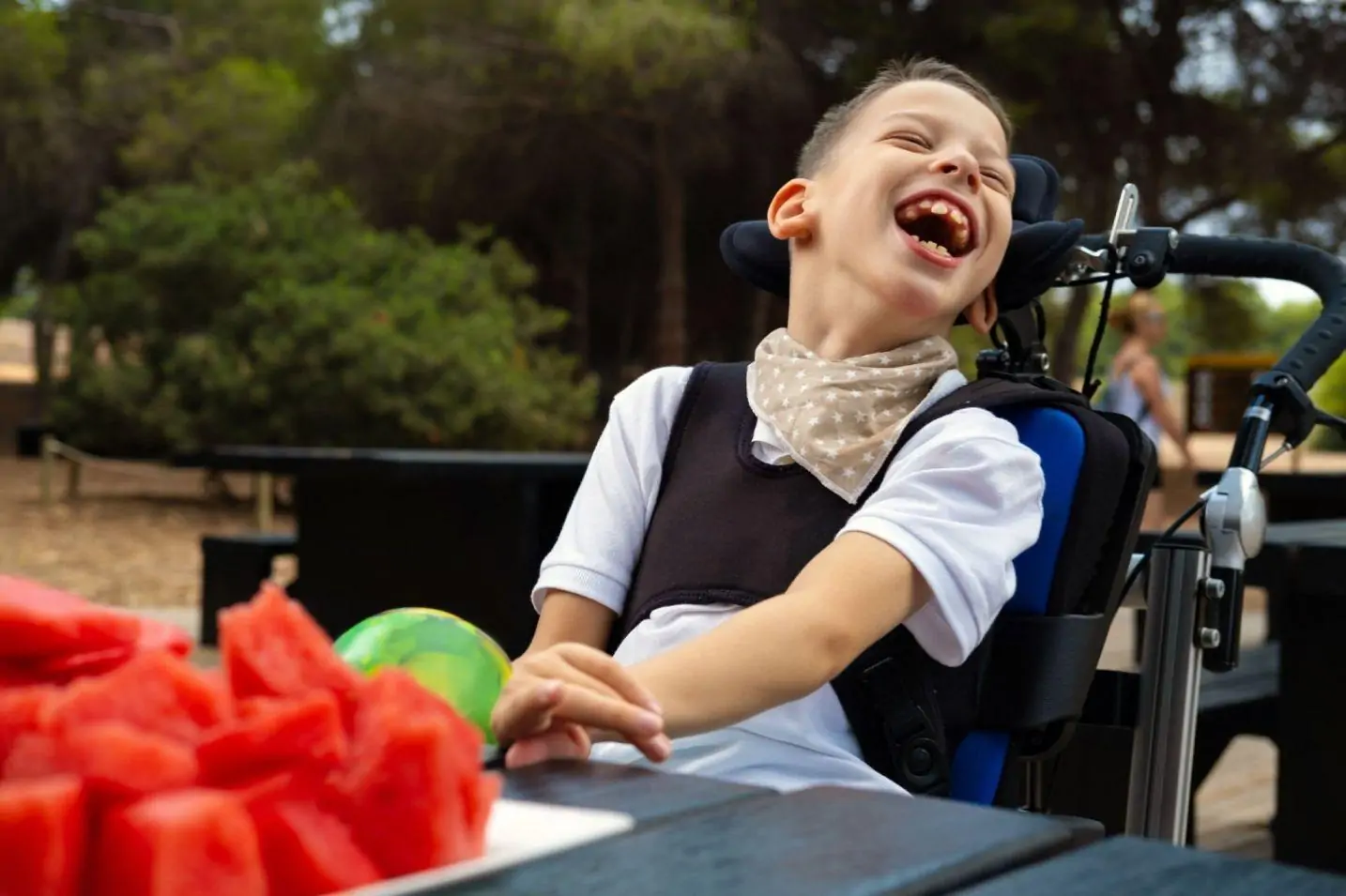 Young boy laughing in a wheelchair outdoors